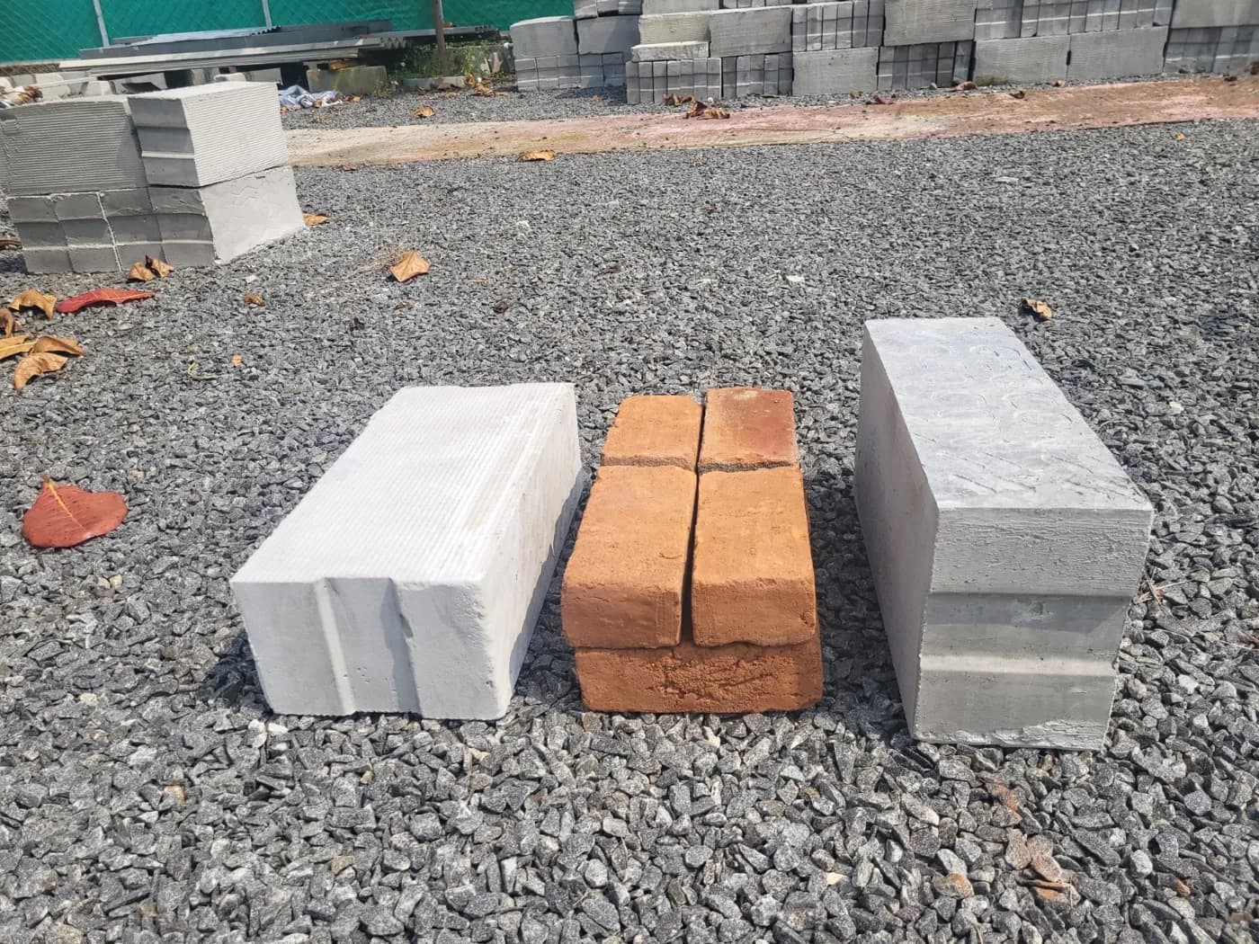 Lightweight blocks and red clay bricks laid side by side on gravel